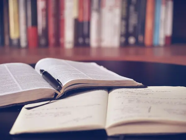 Bücher und Laptop auf einem Schreibtisch als Symbol für Weiterbildung neben dem Beruf
