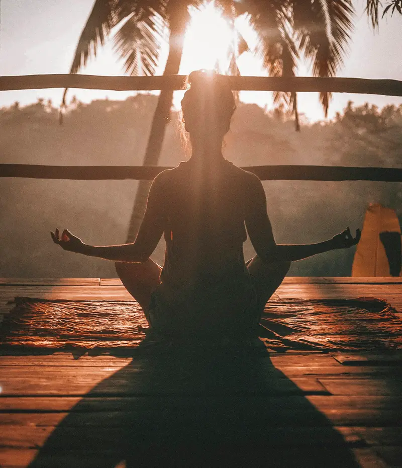 Frau in entspannter Meditationshaltung mit geschlossenen Augen vor weichem Tageslicht